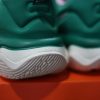 Cận cảnh gót giày của một đôi giày bóng rổ nam Nike Giannis Immortality 3 5 The Hard Way DZ7533-300 màu xanh lá cây và hồng trên hộp màu cam. Thương hiệu 