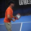 Vợt Pickleball Adidas Adipower Ctrl 3.2 PB1CA0 13 Người đan ông mặc áo màu cam cầm hai tay vào chiếc vợt người đàn ông đang chơi pickleball với cây vợt Adidas Adipower Ctrl 3.2 PB1CA0 chính hãng